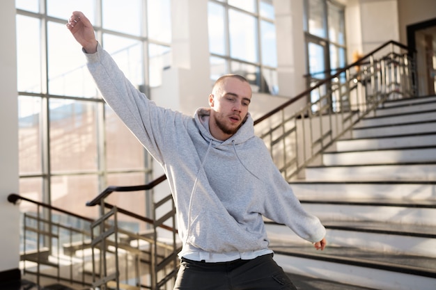 Jonge mannelijke artiest die danst in een gebouw naast trappen