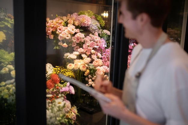 Gratis foto jonge mannelijke bloemist die aantekeningen maakt van de bloemen in de winkel