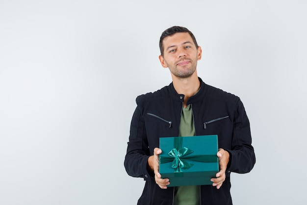 Jonge mannelijke giftdoos in t-shirt, jas en op zoek blij, vooraanzicht.