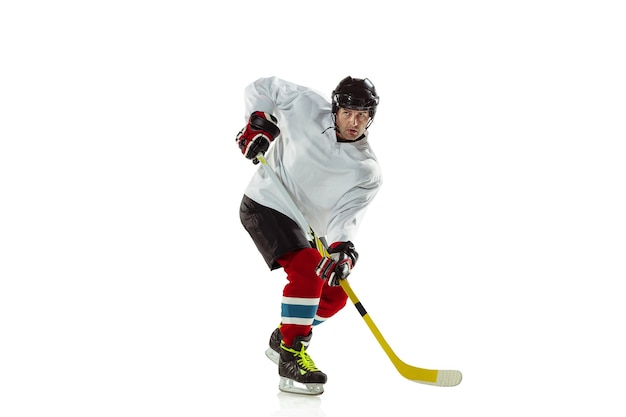 Gratis foto jonge mannelijke hockeyspeler met de stok op ijsbaan en witte achtergrond.
