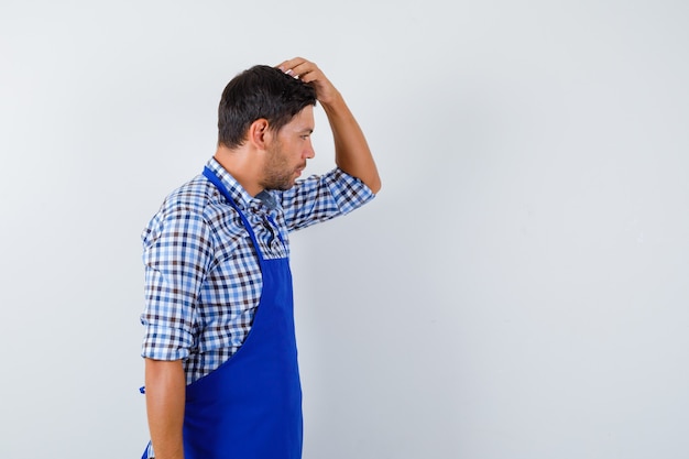 Jonge mannelijke kok in een blauw schort en een overhemd