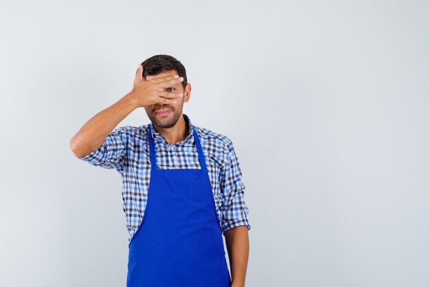 Jonge mannelijke kok in een blauw schort en een overhemd