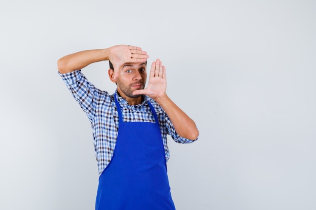 Jonge mannelijke kok in een blauw schort en een overhemd