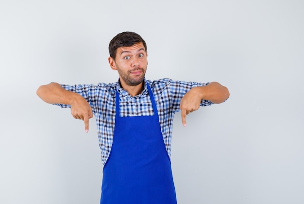 Gratis foto jonge mannelijke kok in een blauw schort en een overhemd