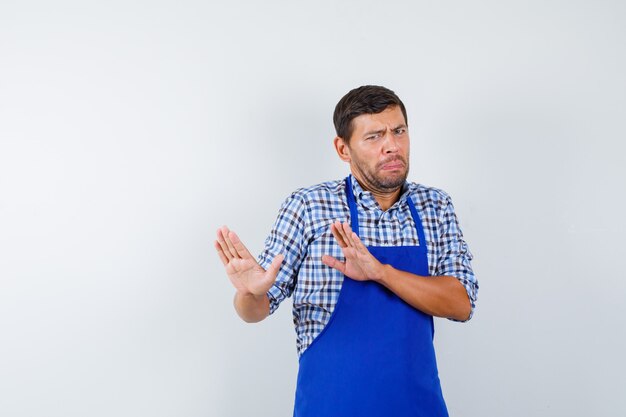 Jonge mannelijke kok in een blauw schort en een overhemd