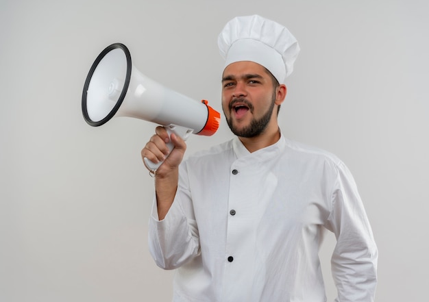 Jonge mannelijke kok in eenvormige chef-kok die in luide spreker het kijken schreeuwt