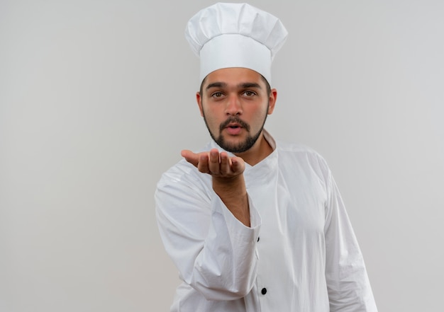 Gratis foto jonge mannelijke kok in eenvormige chef-kok die klapkus naar camera verzendt