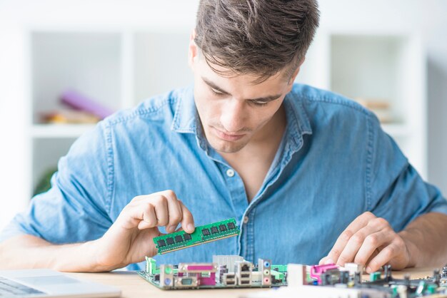 Jonge mannelijke technicus die RAM in motherboard bevestigt