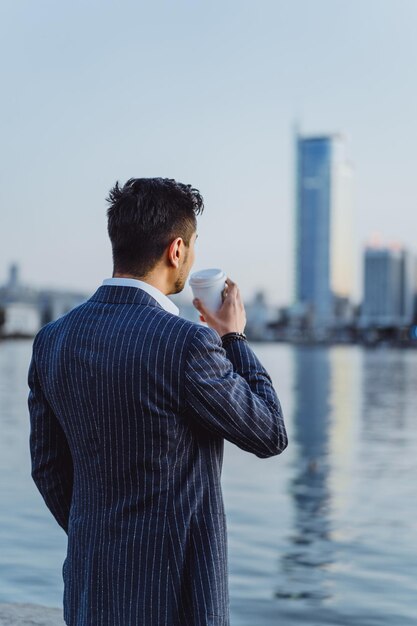 jonge mannelijke zakenman in de stad drinkt koffie in de ochtend op smartphone