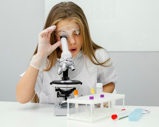 Jonge meisjeswetenschapper die Microscoop met behulp van