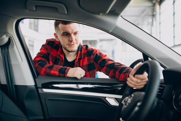 Jonge mens die een auto in een autotoonzaal kiest