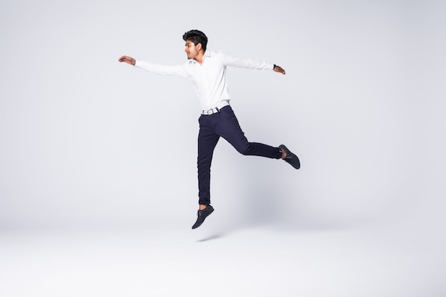 Gratis foto jonge mens die en over witte muur toejuicht springt