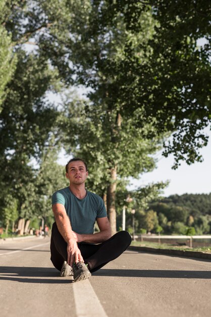 Jonge mens die na het doen van sport in het park rust