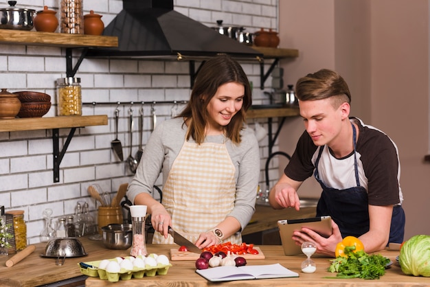 Gratis foto jonge mens die recept toont aan kokend meisje