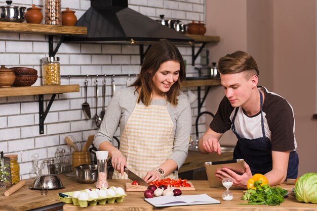 Jonge mens die recept toont aan kokend meisje