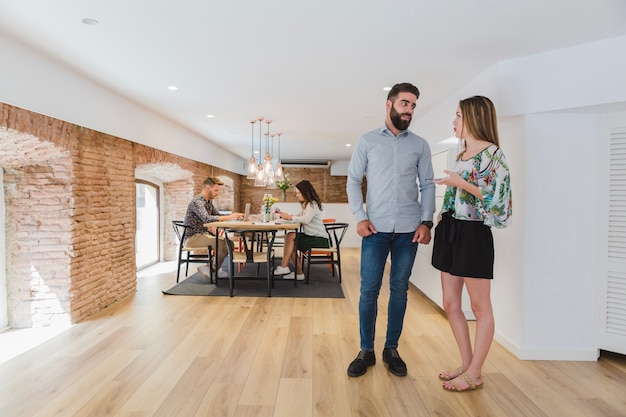 Gratis foto jonge mensen praten op de achtergrond van collega's