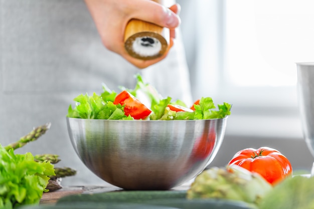 Jonge mensenchef-kok die gezonde salade koken