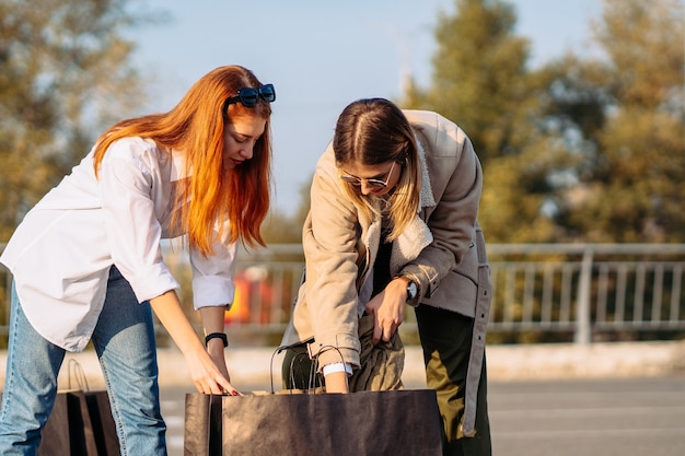 Jonge mode vrouwen met boodschappentassen op parking