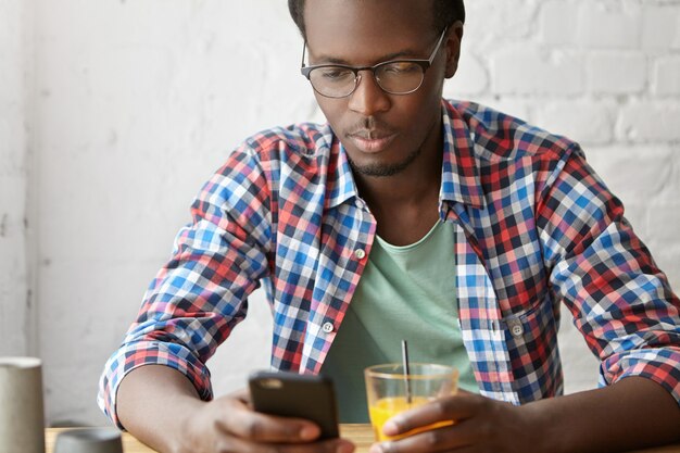 jonge modieuze man zit in een café met telefoon