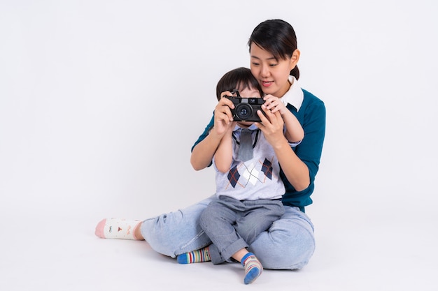 Jonge moeder die haar zoon met camera op wit onderwijst