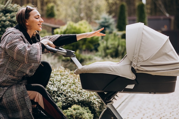 Gratis foto jonge moeder die met kinderwagen in de achtertuin lopen