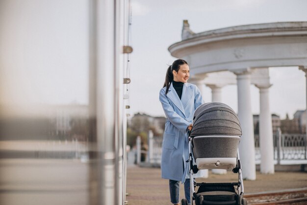 Jonge moeder die met kinderwagen in park loopt