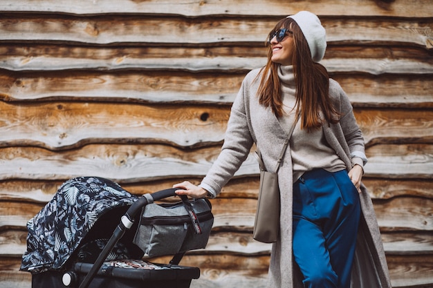 Gratis foto jonge moeder die met kinderwagen in park loopt