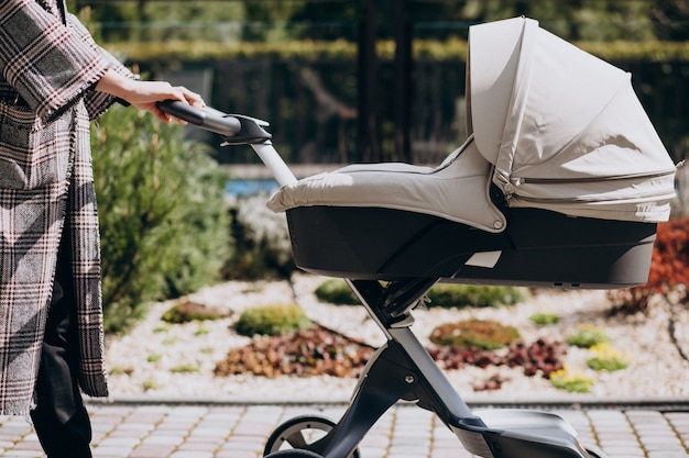 Gratis foto jonge moeder die met kinderwagen in park loopt