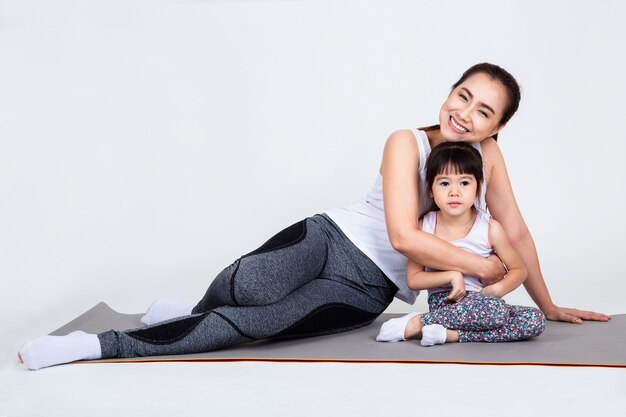 Jonge moeder die mooie dochter met yoga opleidt