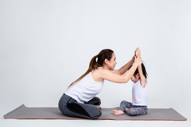Jonge moeder die mooie dochter met yoga opleidt