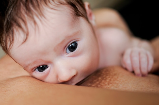 Jonge moeder die pasgeboren baby thuis de borst geeft