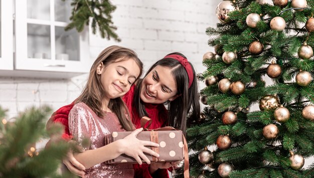 Jonge moeder en dochtertje met een kerstcadeau, het kind verheugt zich over het kerstcadeau.