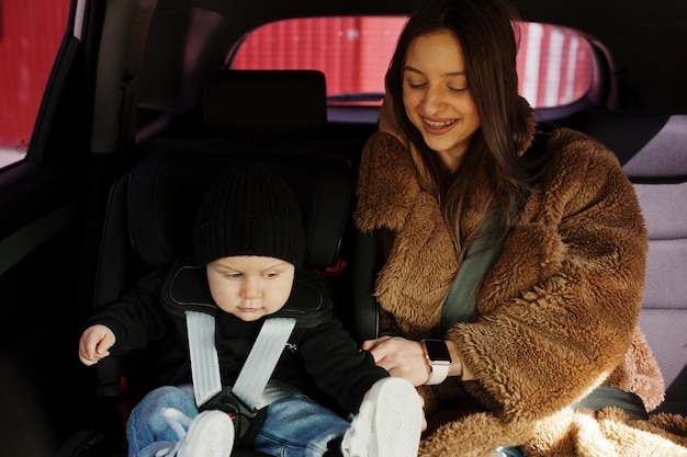 Jonge moeder en kind in auto babyzitje op stoel veiligheidsconcept voor rijden