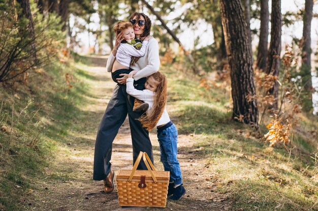 Jonge moeder met dochter en zoon wandelen voor picknick in het bos