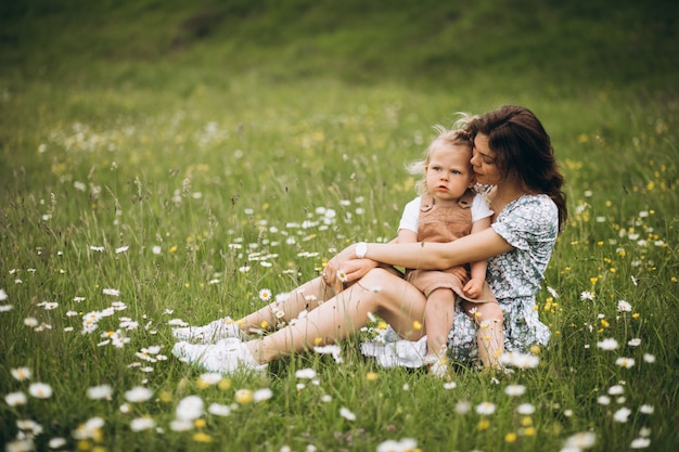 Jonge moeder met dochtertje in park zittend op gras