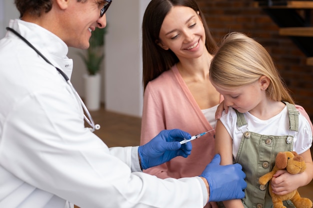 Jonge moeder met haar dochter bij de kinderarts voor een vaccin