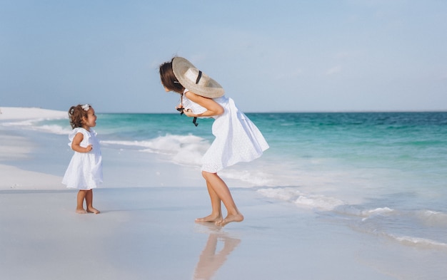 Jonge moeder met haar dochtertje op het strand aan de oceaan