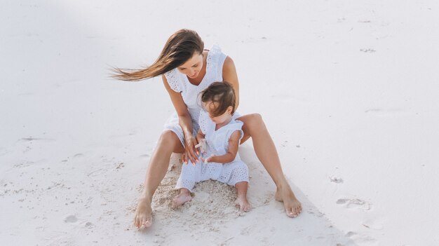 Jonge moeder met haar dochtertje op het strand aan de oceaan