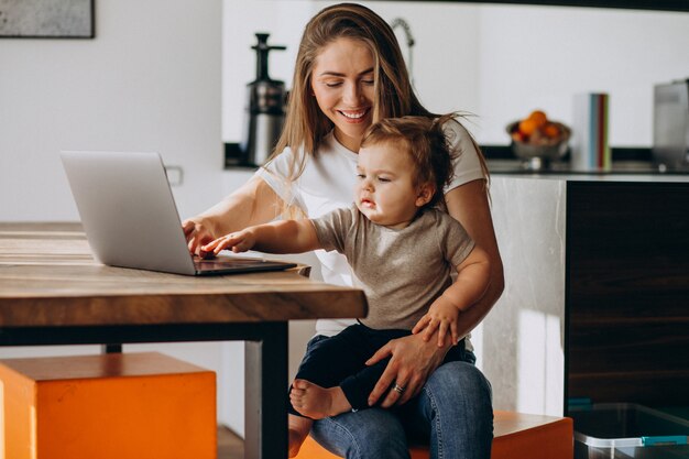 Jonge moeder werkt vanuit huis op laptop met haar zoontje