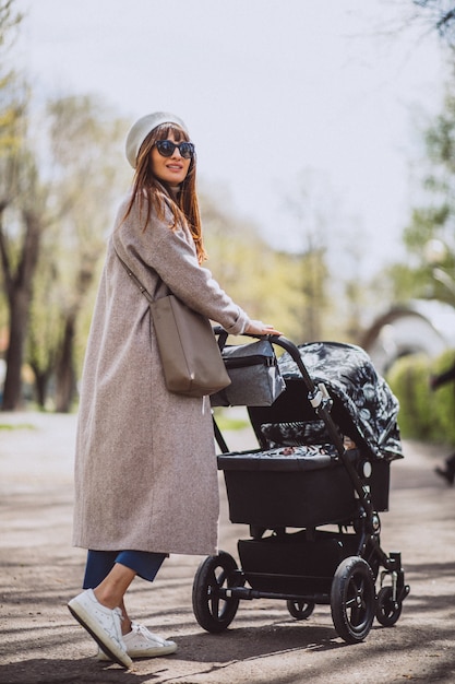 Jonge moeder zit met kinderwagen in park