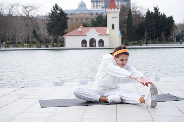 Jonge mooie atleet zittend op de yogamat en haar lichaam uitrekkende foto van hoge kwaliteit