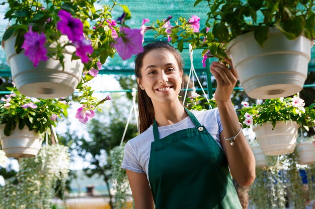 Jonge mooie bloemist poseren, glimlachend onder bloemen.