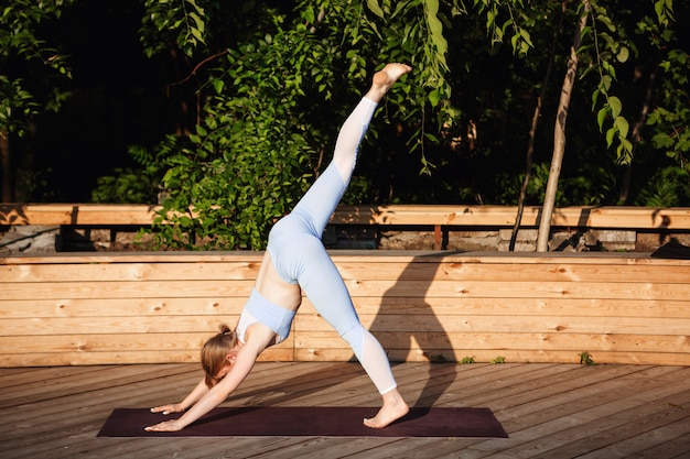 Jonge mooie blonde meisje beoefenen van yoga buiten bij zonsopgang.