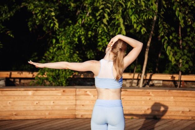 Jonge mooie blonde meisje beoefenen van yoga buiten bij zonsopgang.