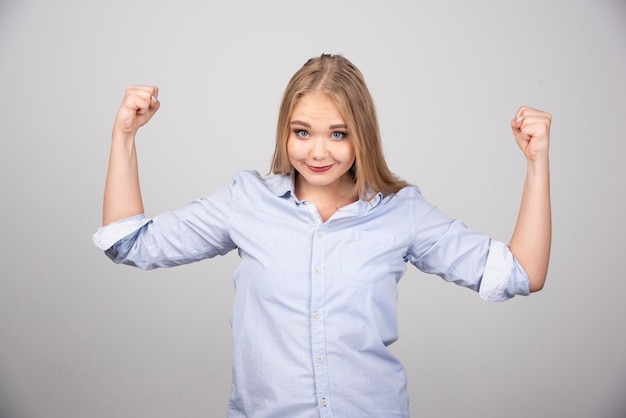 Jonge mooie blonde vrouw permanent en weergegeven: arm spier.