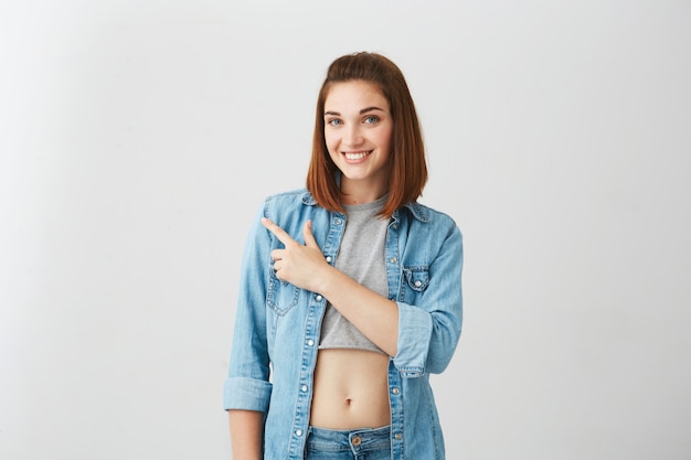 Jonge mooie brunette meisje glimlachend wijzende vinger aan de zijkant.