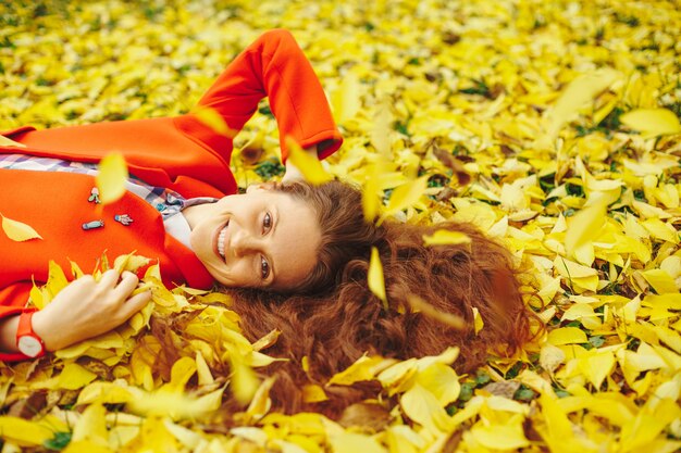 Jonge mooie dame omringd de herfstbladeren