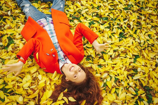 Jonge mooie dame omringd de herfstbladeren