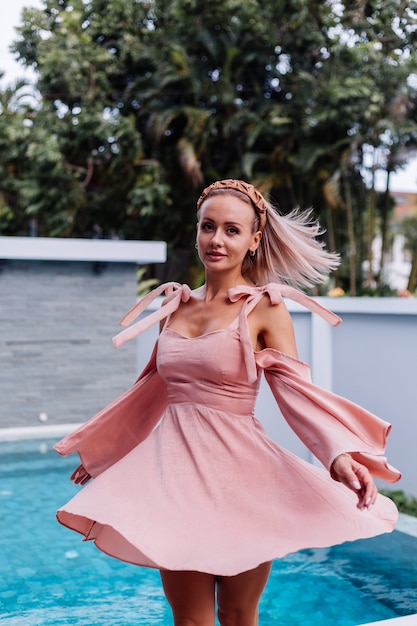 Jonge mooie Kaukasische romantische vrouw alleen in schattige zomerjurk op vakantie in luxevilla