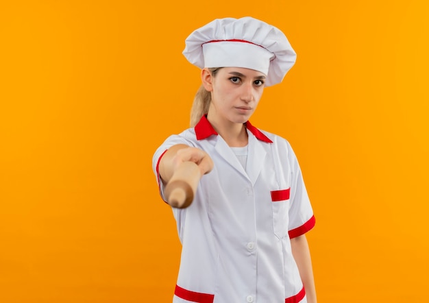 Gratis foto jonge mooie kok in uniform chef-kok deegroller uitrekken